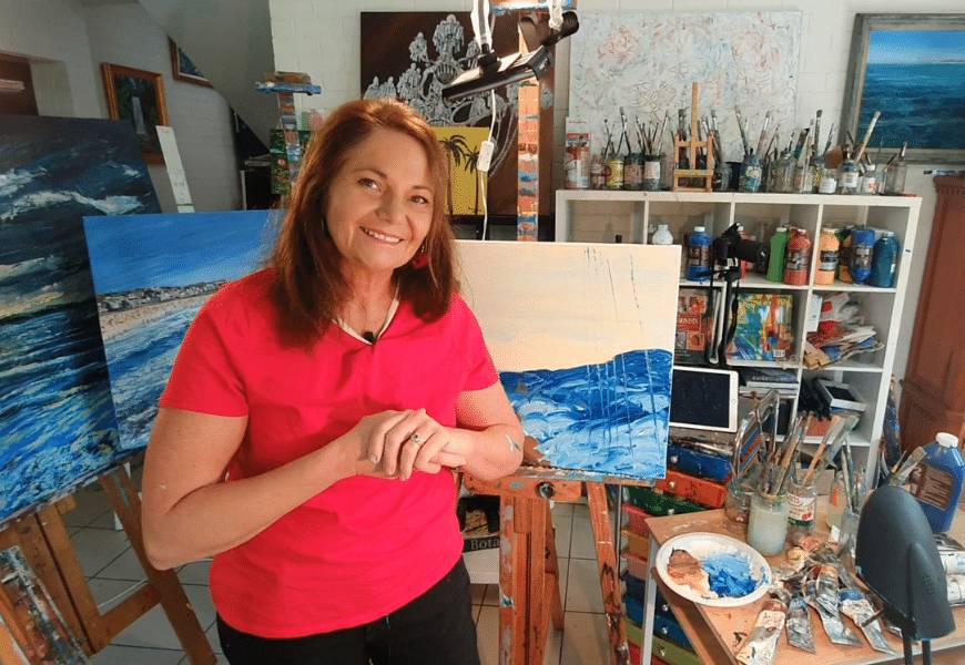 Artist Donna Gibb surrounded by paintings in her art studio